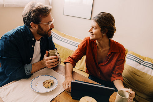 Couple talking over coffee and cookies in cozy living room
