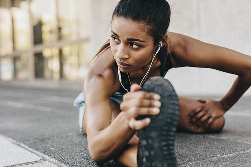 Woman athlete stretching her legs during warm up