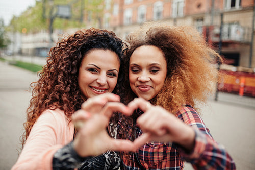 Beautiful young women making heart shape