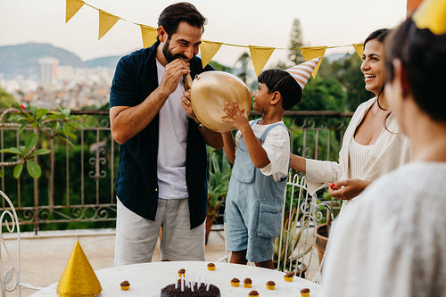 Family celebrating a birthday outdoors with balloons and festive decor
