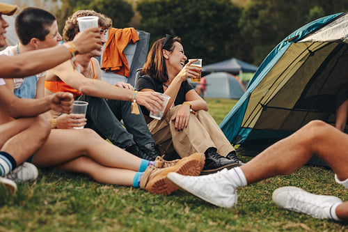 Group of friends raising beer cups, celebrating at a summer music festival