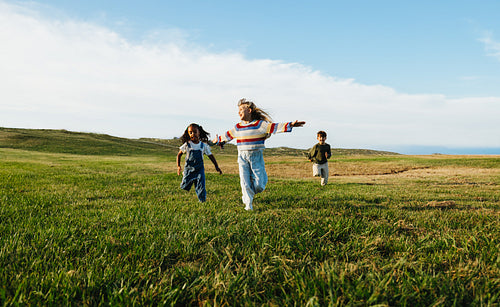 Children running freely together across open meadow outdoors