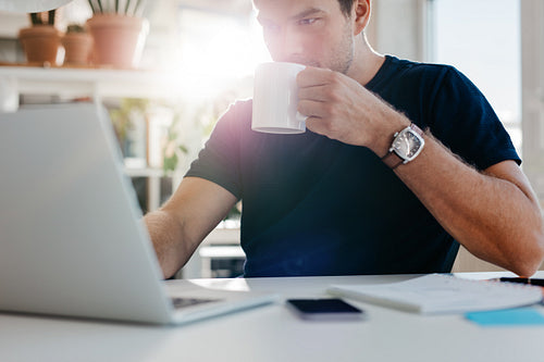 Young businessman with cup of coffee at work