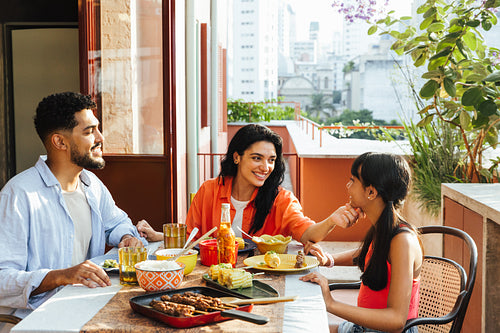 Latin American family enjoying an outdoor meal on a sunny day in the city