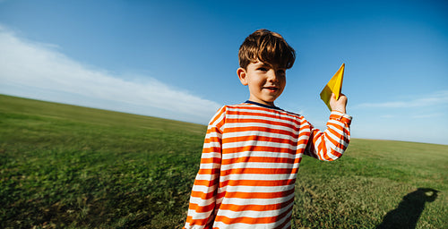 Boy with paper plane outdoors
