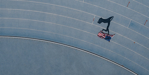 Athlete running on the track holding flag celebrating win