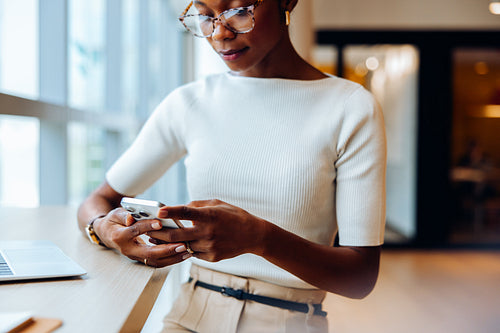 Professional woman using smartphone at desk in bright office setting