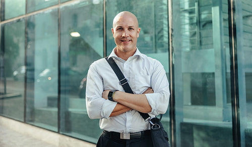 Successful businessman smiling at the camera outside his workplace