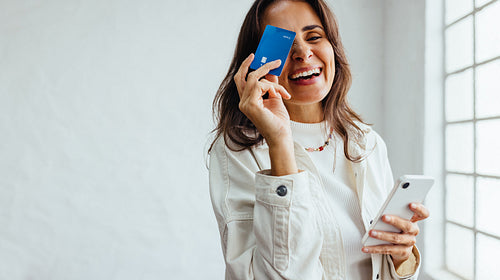 Online banking for business professionals: Happy business woman holding a credit card and a mobile phone