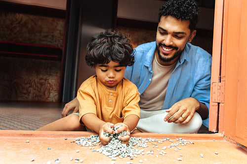 Father and son spending quality time together playing with pebbles