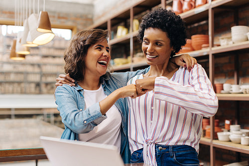 Successful ceramists fist bumping each other in their store