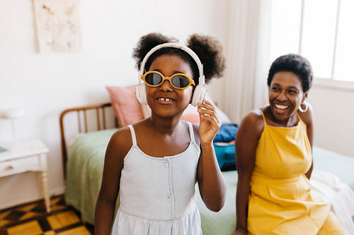 Young black girl listening to music on headphones, wearing cool sunglasses