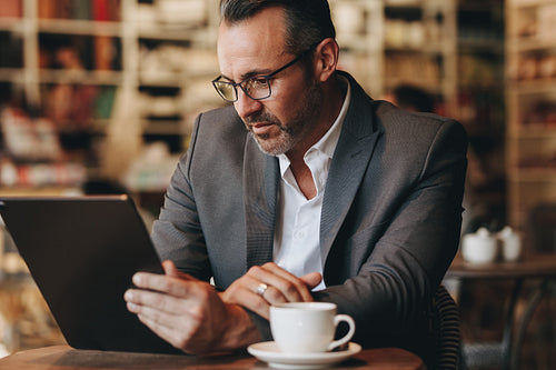 Businessman at cafe working on digital tablet