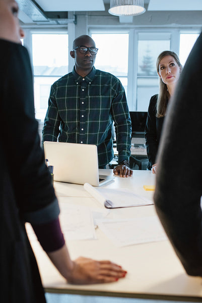 Young people standing at a table discussing work