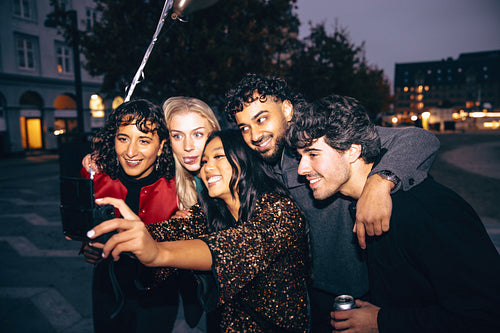 Friends taking a group selfie on a lively evening in the city