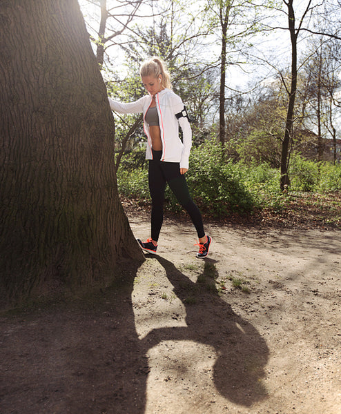 Young woman stretching before a jog in forest