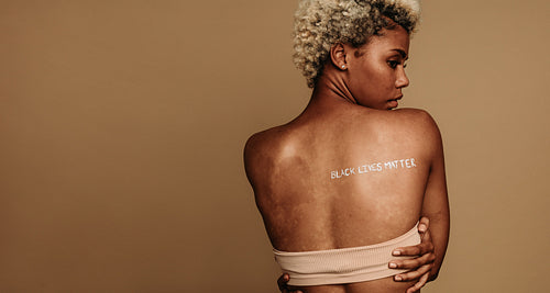 Portrait of african american woman with black lives matter painted on back