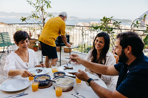 Friends enjoying a barbecue on a sunny terrace overlooking the sea