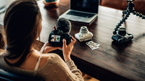 Young female blogger watching her recorded content on camera