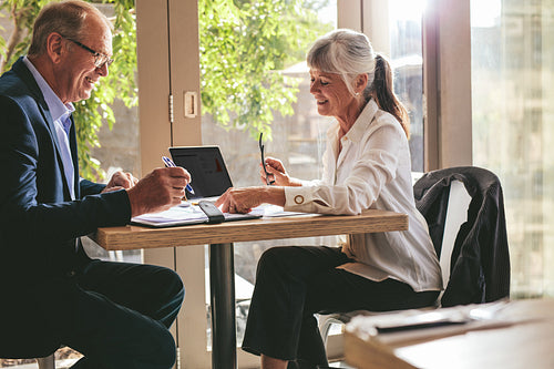 Business partners signing a contract at a coffee shop