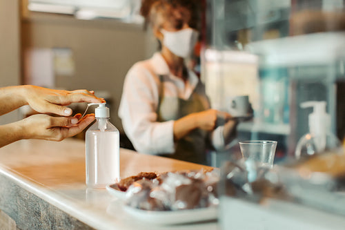 Female customer sanitizing her hands in a coffee shop