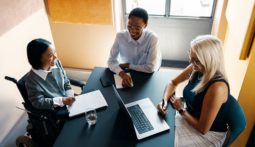Professional team collaborating in a meeting around a laptop in natural light
