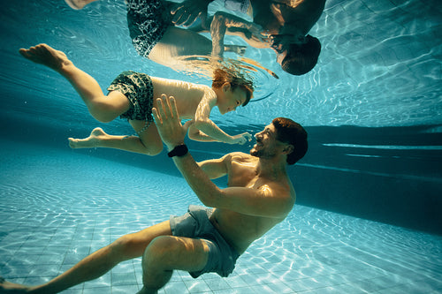 Father and child enjoying playful swim underwater in pool