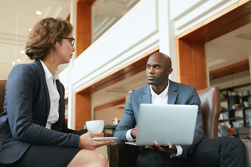 Two businesspeople having meeting in cafe with laptop