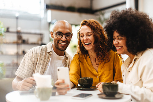Friends making a video call with a mobile phone on a coffee date