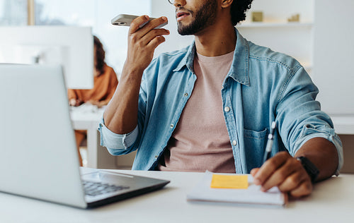 Young businessman speaking on smartphone at modern office