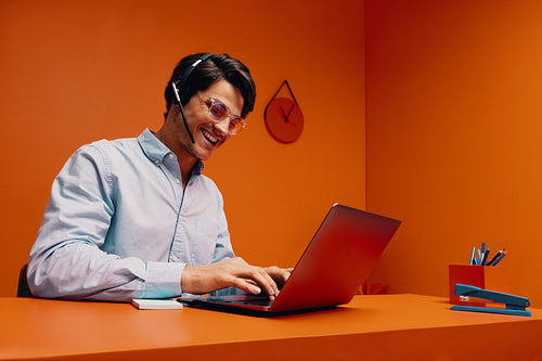 Customer service representative instructing and typing on laptop while smiling in bright office setting