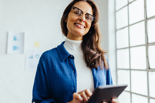 Creative business woman smiling and using a tablet in an office