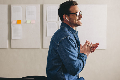 Cheerful businessman having a conference call using earbuds