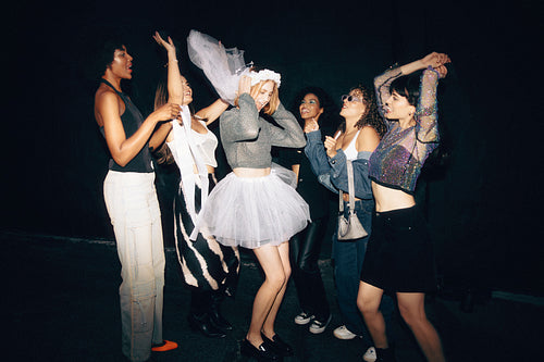 Group of cheerful women celebrating a bachelorette party together at night