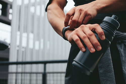 Man with water bottle using a smartwatch to monitor his progress
