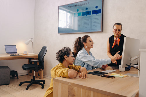 Three coworkers discussing a project in a modern office environment