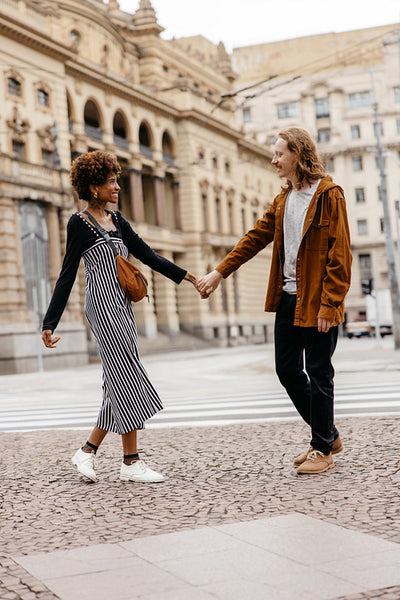 Affectionate couple holding hands walking through city streets