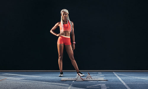 Woman sprinter standing on a running track