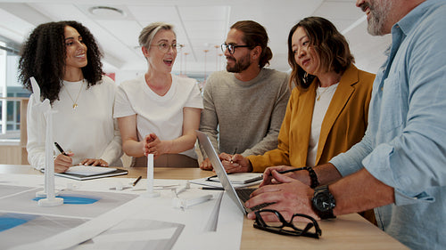 Success in sustainability: Happy engineering team celebrating completing a wind energy project in an office