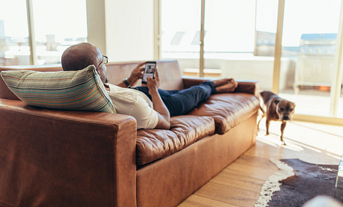 Man lying on lounge using mobile phone