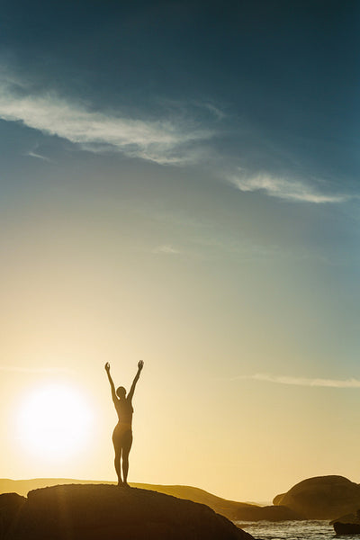 Silhouette of a woman at the beach with her hands raised