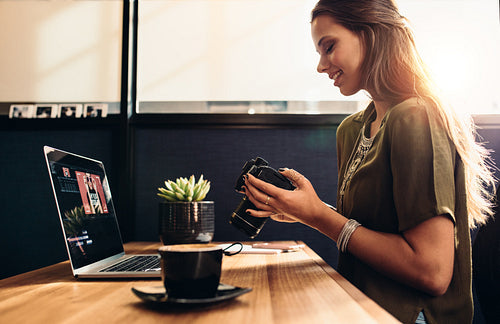 Young female vlogger watching her camera while editing her vlog on computer.