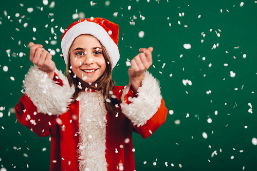 Girl in santa claus dress enjoying artificial snowfall