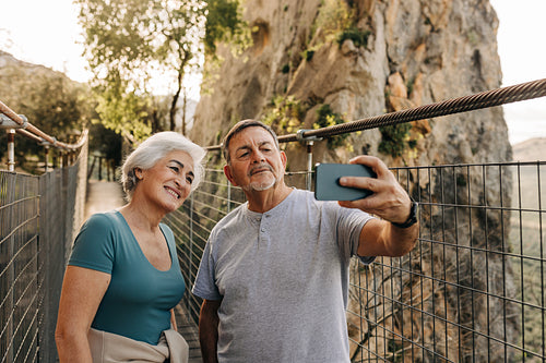 Senior couple taking a selfie together on a bridge
