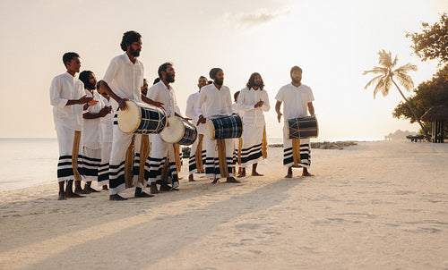 Traditional Maldivian boduberu drummers performing on a tropical beach at sunset