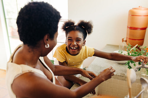 family fun between mother and daughter as they wash hands in a Brazilian kitchen