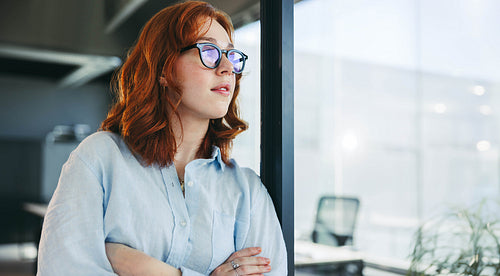 Confident professional woman with crossed arms in a tech office