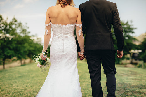 Bride and groom walking in park