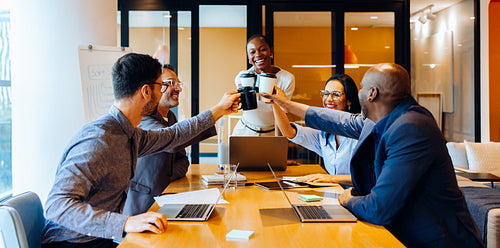 Happy professionals toasting coffee cups during a meeting in high spirits