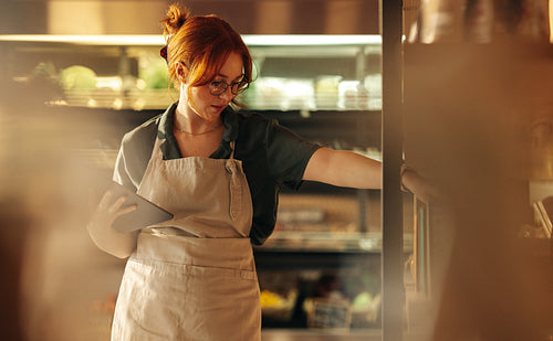 Young supermarket owner stocktaking using a digital tablet